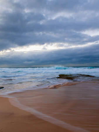 Wave flow into the sand in a stormy morning at the beach.の写真素材
