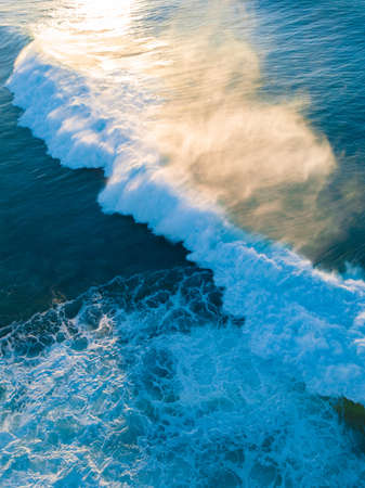 Wave breaking with shimmering of morning sunlight.の写真素材
