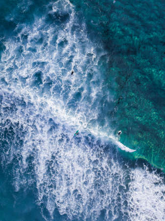 Aerial view of people surfing the wave.