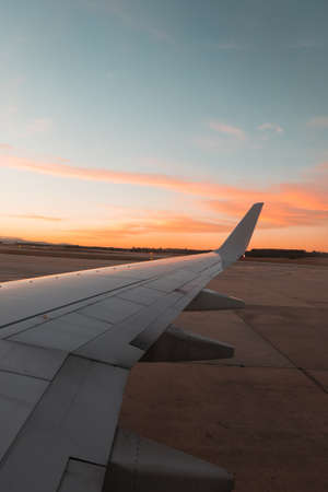 Airplane wing with sunset sky in the background.