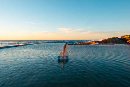 Empty South Curl Curl rock pool in the morning with clear blue sky.