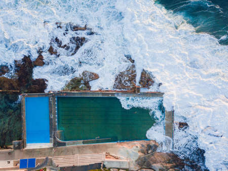 Top down aerial view of Dee Why rock pool with incoming wave. Sydney, Australia.