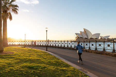 Sydney, Australia - July 19, 2018: People running along Sydney Harbour in the morning. Sydney Opera House on the background.のeditorial素材