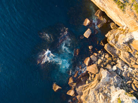 Top down aerial view of rock cliff in with blue water.の写真素材