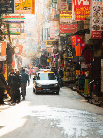 Kathmandu, Nepal - December 6, 2018: Taxi passing through busy Thamel market during the day.のeditorial素材