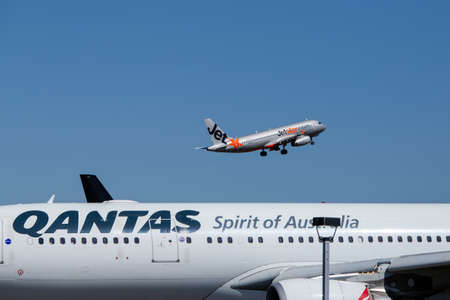 Sydney, Australia - February 12, 2019: Jetstar Airbus A320 flying above Qantas aircraft at Kingsford Smith Sydney International airport.のeditorial素材