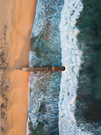 Top down aerial view of wave coming into beach shore with stormwater pipe.の写真素材