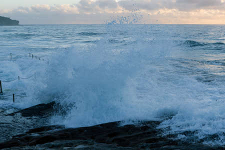 Wave crashing into rocky coastline.