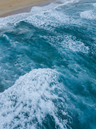 Top down view aerial of waves coming into the coast.