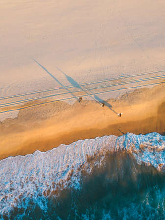 Aerial view of three people with shadow on  the beach coastline.の写真素材