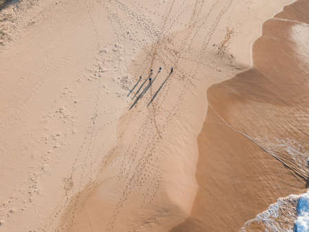 Five people walking on the sand with long shadow.の写真素材