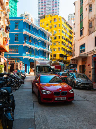 Hong Kong - October 4, 2019: A red car in front of blue and yellow building at Stone Nullah Ln, Wan Chai.のeditorial素材