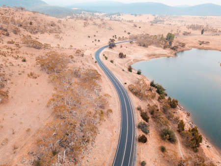Aerial view of curve road around a dry hill.
