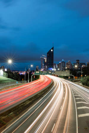 Brisbane, Australia - January 25, 2020: Car light trails at M3 with city skyline on the background.のeditorial素材