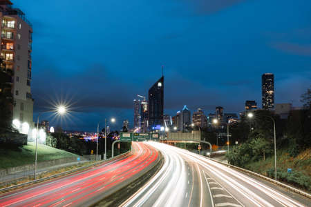 Brisbane, Australia - January 25, 2020: Car light trails at M3 with city skyline on the background.のeditorial素材