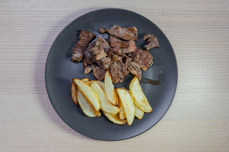 A plate of grilled beef and baked potatoes.の写真素材