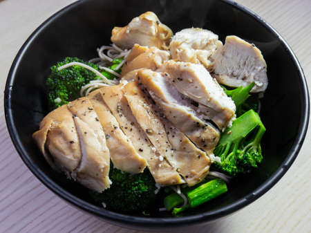 A bowl of chicken breast with broccoli on the side.の写真素材