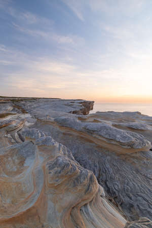 Rock cliff view with cloudy blue sky.