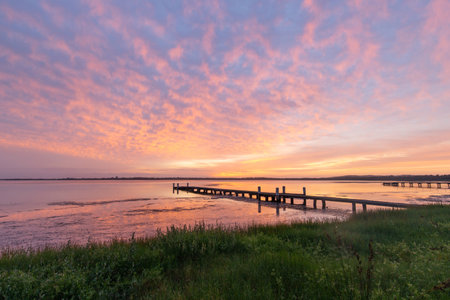 Colorful sunrise cloud over a jetty on the lake side.の写真素材