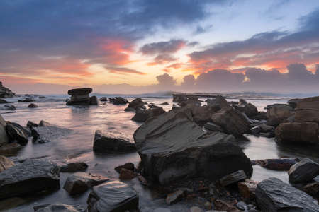 Dawn view of rocky beach shore.
