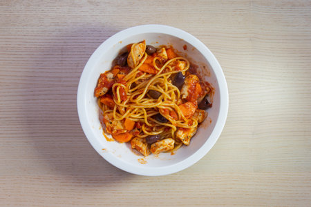 A bowl of chicken spaghetti with tomato sauce.の写真素材