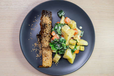 A plate of salmon with roasted vegetables.の写真素材
