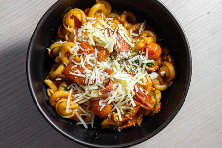 A bowl of pasta topped with shredded cheese.の写真素材