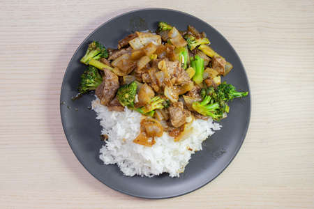 A plate of beef and broccoli stir fry with steam rice.の写真素材