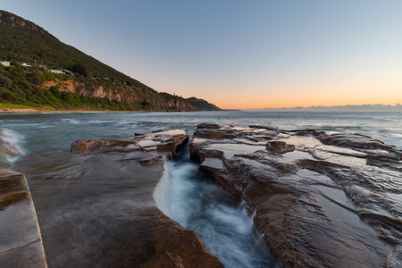 Water flowing between rocks on the beach shore.の写真素材