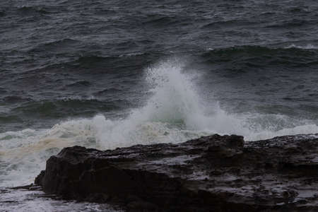 Small wave breaking on the rocky shore.の写真素材
