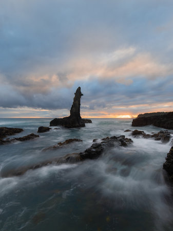 Cloudy sunrise at rocky seascape shore.の写真素材