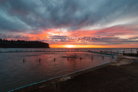 Colorful sky over Bilgola Beach rock pool at dawn, Sydney, Australia.の写真素材