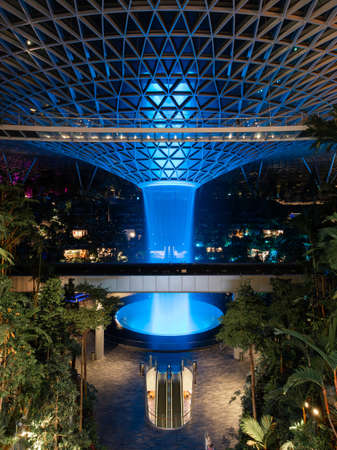 Singapore - May 19, 2022: Indoor waterfall at Jewel Changi Airport light up in blue.のeditorial素材