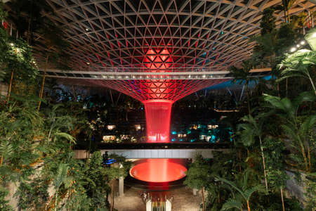 Singapore - May 19, 2022: Indoor waterfall at Jewel Changi Airport light up in red.のeditorial素材