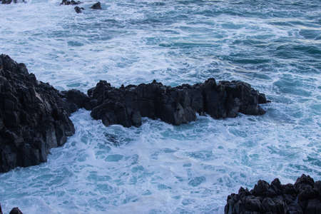 Ocean water around small rock formation.の写真素材
