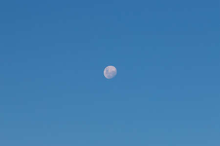 Waning gibbous moon on clear blue sky.の写真素材