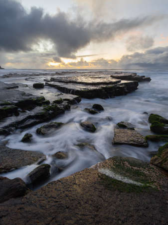 High tide ocean water flowing around rocks.