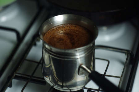 Silver boiling cezve (briki) with ground coffee. Turkish coffee brewing pot