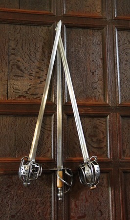 Three Ancient Swords Mounted on a Wood Panelled Wall の写真素材