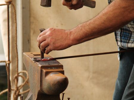 A Blacksmith Hammering a Piece of Red Hot Metal.