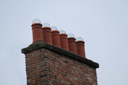 A Row of Six Terracotta Chimney Pots with Net Coverings.の写真素材
