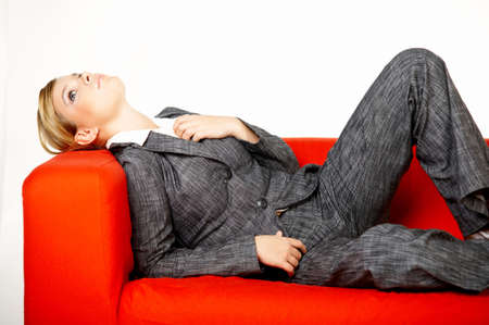Young business woman is resting on the red couchの写真素材