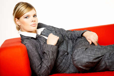 Young business woman is resting on the red couchの写真素材