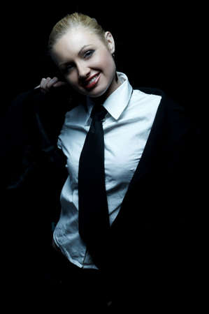 Beautiful business woman wearing black tie and jacket isolated on black backgroundの写真素材