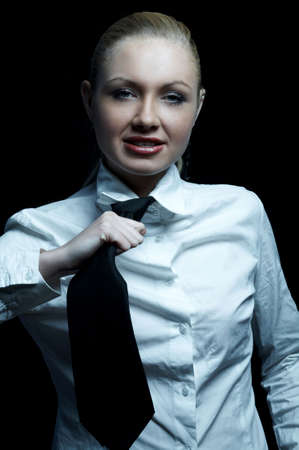 Beautiful business woman wearing black tie and white shirt isolated on black backgroundの写真素材