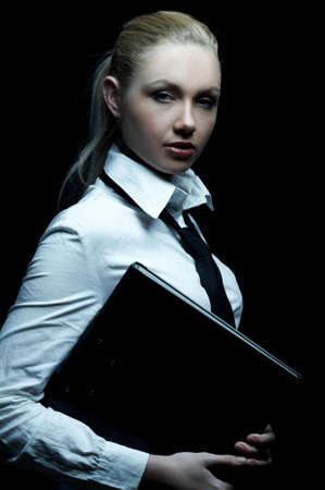 Beautiful business woman wearing black tie and white shirt holding folder isolated on black backgroundの写真素材