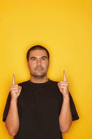 25-30 years old handsome caucasian man posing at yellow background, pointing by fingers