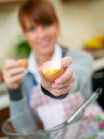 Beautiful woman in kitchen is making a cakeの写真素材