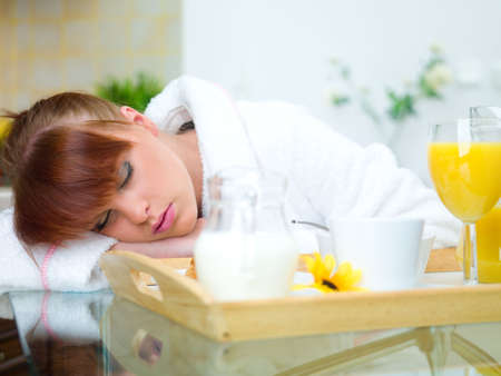 Beautiful woman in kitchen sleeping on tableの写真素材