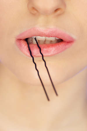 Portrait of beautiful woman with hairpin in mouthの写真素材